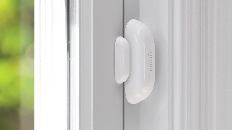 White oval smart sensor mounted on a white door.