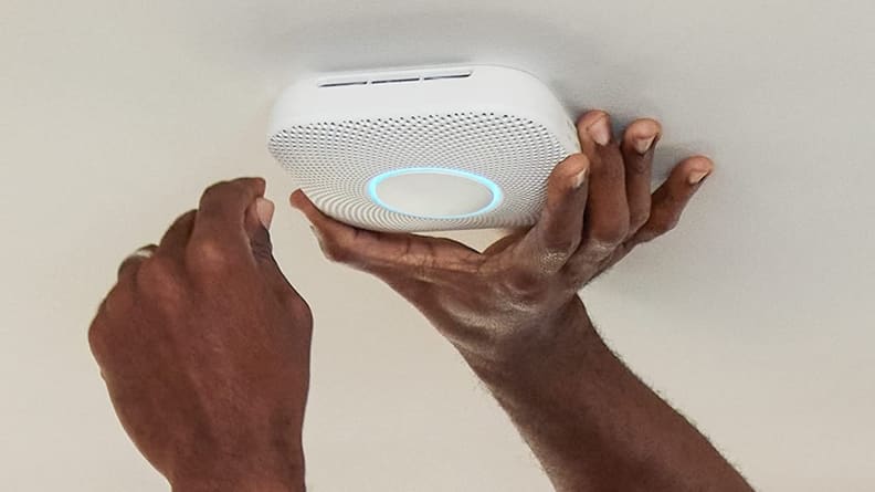 Person using hands to install smart smoke detector on the wall.