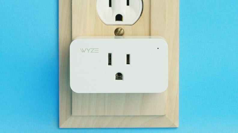 White rectangular wall socket plugged into an outlet on a blue wall.