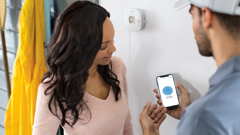 Person smiling while another person viewing display on phone screen.